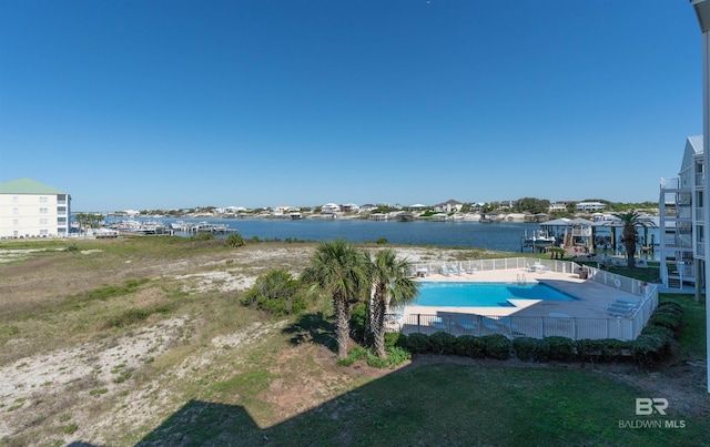 community pool with a water view and fence