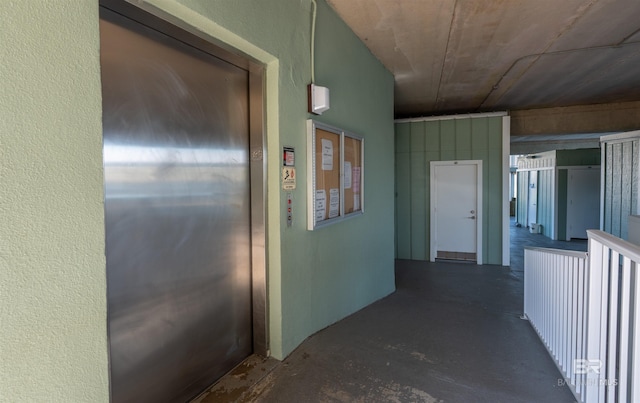 hallway with unfinished concrete flooring and elevator