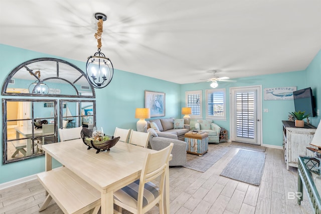 dining room featuring light wood-style flooring, baseboards, and ceiling fan with notable chandelier