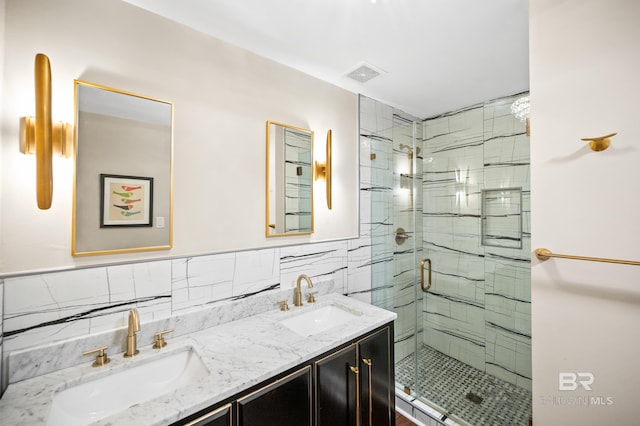 bathroom featuring dual vanity, decorative backsplash, walk in shower, and tile walls