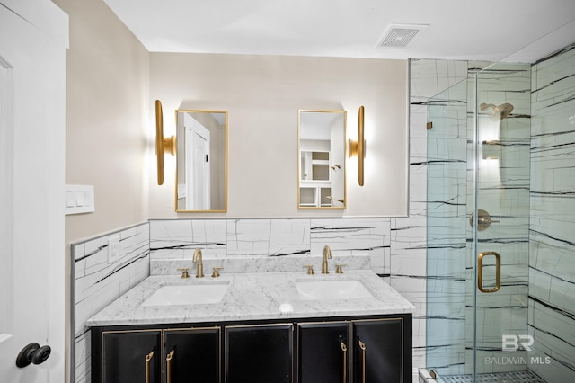 bathroom featuring a shower with shower door, decorative backsplash, tile walls, and double sink vanity