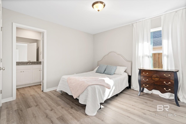 bedroom with light hardwood / wood-style floors and ensuite bath