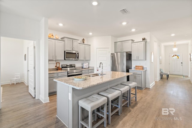 4299 Montague Dr, Gulf Shores, AL 36542 - kitchen with stainless steel appliances, a sink, gray cabinetry, a breakfast bar, and recessed lighting