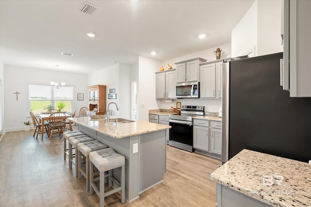 4299 Montague Dr, Gulf Shores, AL 36542 - kitchen with appliances with stainless steel finishes, a sink, gray cabinets, a breakfast bar area, and light wood-style flooring