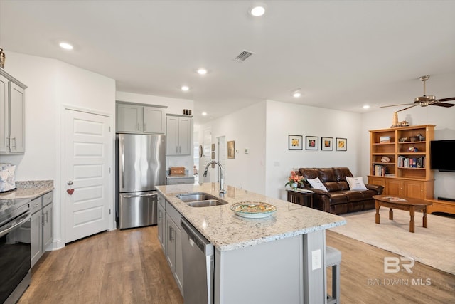 4299 Montague Dr, Gulf Shores, AL 36542 - kitchen featuring stainless steel appliances, a sink, gray cabinetry, light wood-type flooring, and light stone counters
