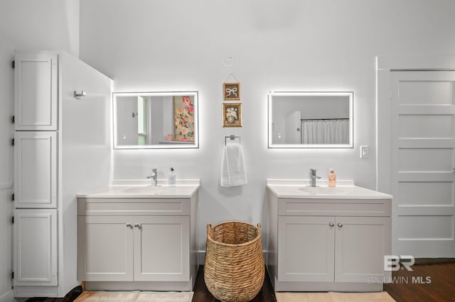 full bath with wood finished floors, a sink, and two vanities