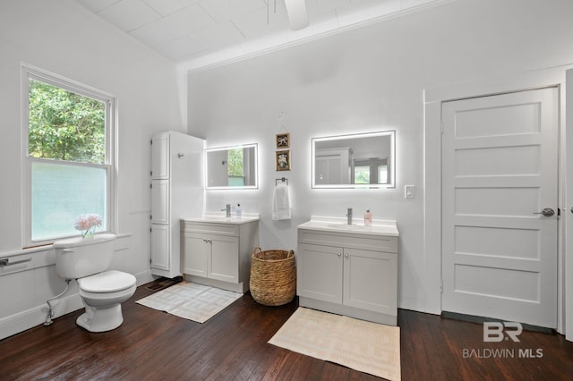 full bathroom with a sink, two vanities, toilet, and hardwood / wood-style flooring