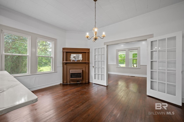 unfurnished dining area featuring ornamental molding, heating unit, baseboards, a chandelier, and hardwood / wood-style flooring