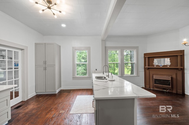 kitchen with a sink, dark wood-style flooring, a notable chandelier, and light stone countertops