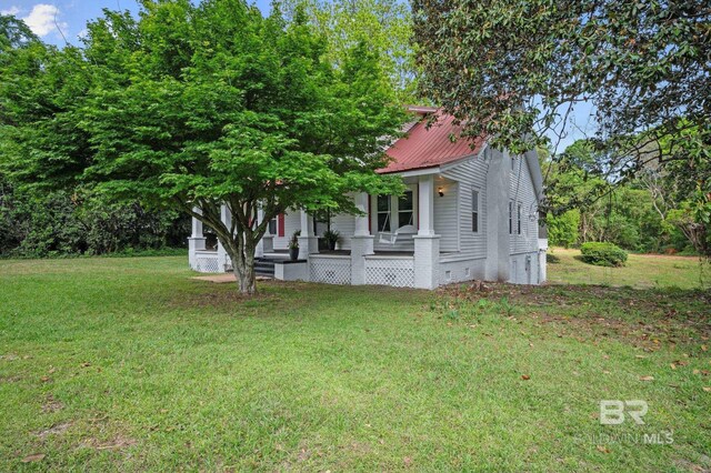view of front of property with a porch, a front lawn, crawl space, and metal roof