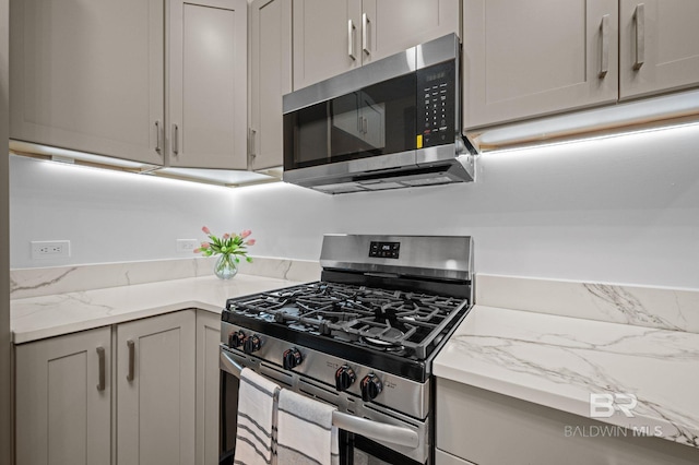 kitchen featuring gray cabinetry, appliances with stainless steel finishes, and light stone countertops