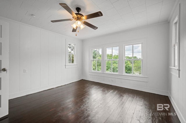 spare room featuring ornamental molding, a decorative wall, hardwood / wood-style floors, baseboards, and a ceiling fan