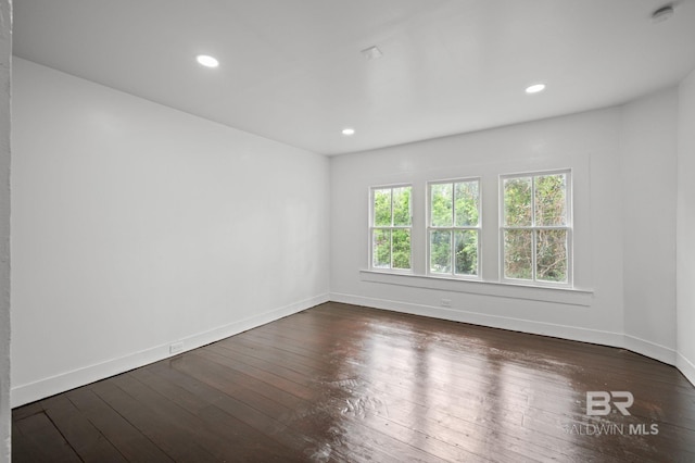 spare room with recessed lighting, baseboards, and dark wood finished floors
