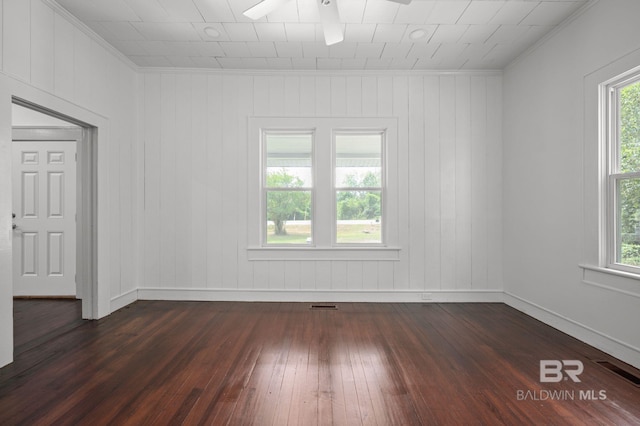 spare room featuring crown molding, dark wood-style flooring, ceiling fan, and a healthy amount of sunlight