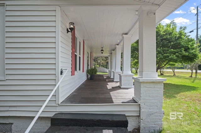 wooden terrace featuring a porch and a yard