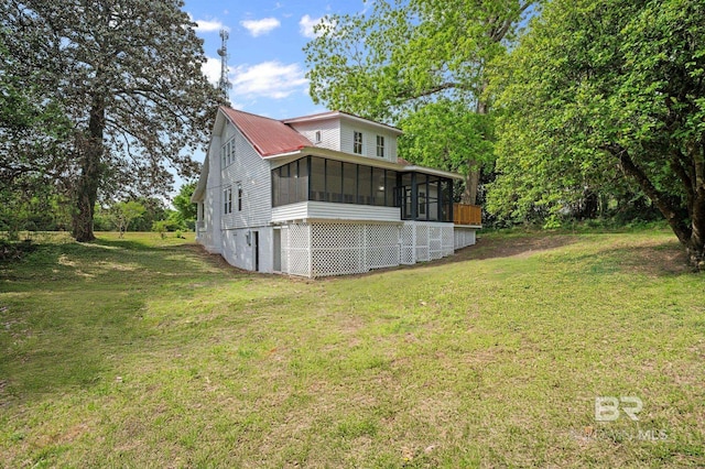 rear view of house featuring a lawn and a sunroom