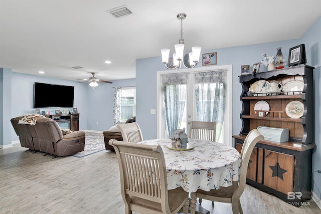 dining space featuring ceiling fan with notable chandelier and light hardwood / wood-style flooring