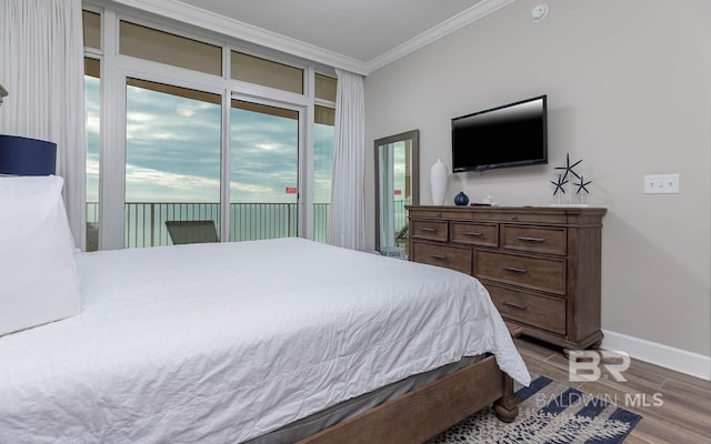 bedroom featuring wood-type flooring, crown molding, and access to outside