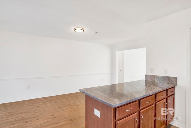 kitchen featuring light stone counters, light hardwood / wood-style flooring, and kitchen peninsula