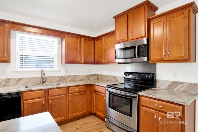 kitchen with light hardwood / wood-style floors, stainless steel appliances, light stone countertops, and sink