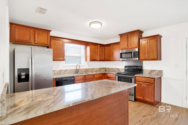 kitchen featuring sink, stainless steel appliances, light stone countertops, kitchen peninsula, and light wood-type flooring