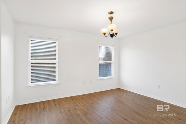 spare room with hardwood / wood-style flooring and a notable chandelier