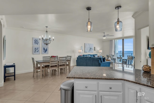 kitchen featuring baseboards, light tile patterned floors, ceiling fan with notable chandelier, white cabinetry, and a peninsula