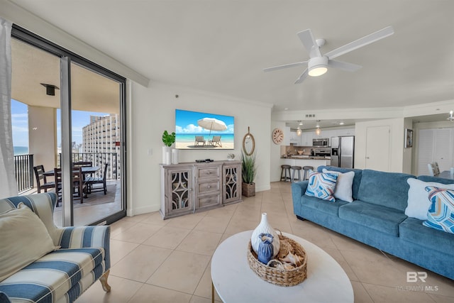 living area featuring crown molding, baseboards, light tile patterned flooring, and ceiling fan