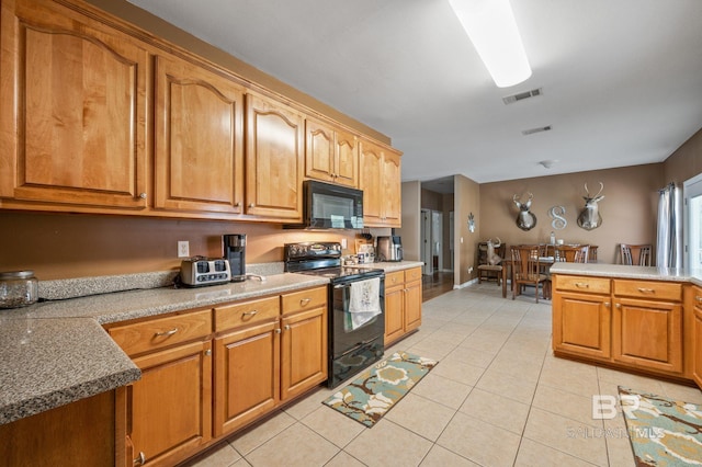 kitchen featuring kitchen peninsula, light tile patterned flooring, and black appliances