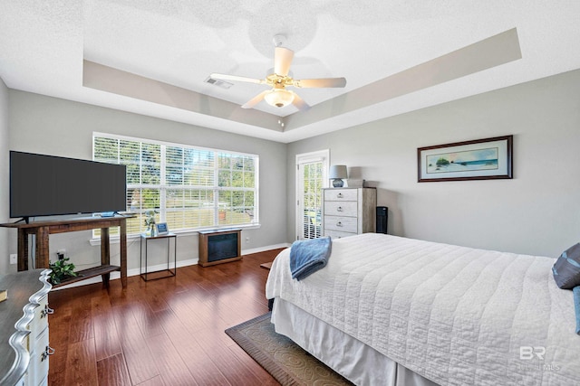 bedroom with a raised ceiling, multiple windows, ceiling fan, and a textured ceiling