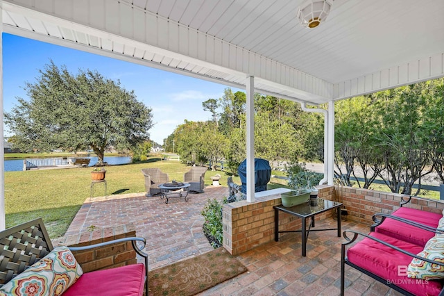 view of patio / terrace featuring area for grilling, a water view, and an outdoor living space with a fire pit