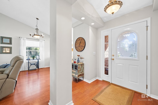 entryway with hardwood / wood-style flooring, a notable chandelier, and vaulted ceiling