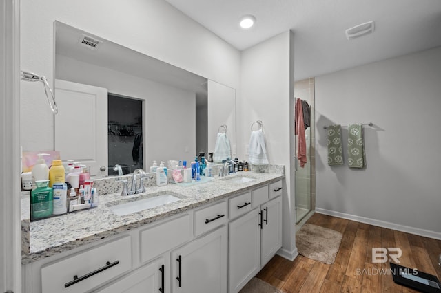 bathroom with a sink, visible vents, a stall shower, and wood finished floors