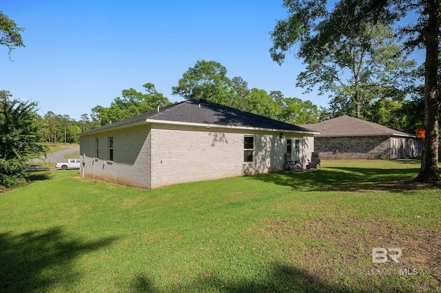 back of house with brick siding and a lawn