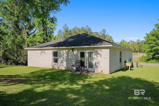 rear view of property featuring a lawn and brick siding