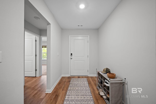 foyer entrance featuring wood finished floors, baseboards, and visible vents