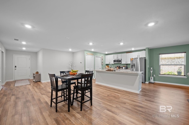 dining room with light wood-style flooring, baseboards, and recessed lighting