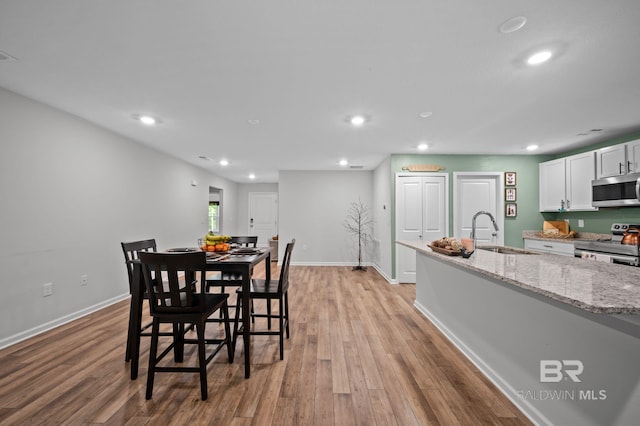 dining space with light wood finished floors, baseboards, and recessed lighting