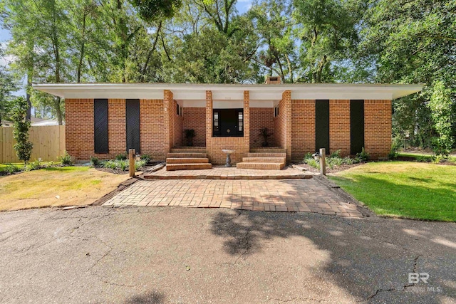 mid-century home with brick siding, a front lawn, and fence