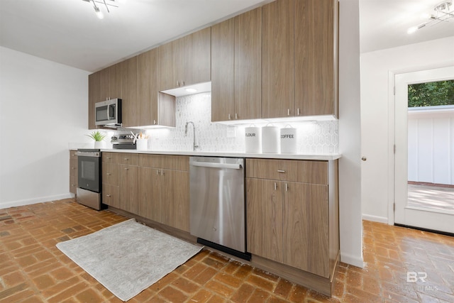 kitchen with backsplash, baseboards, stainless steel appliances, and light countertops