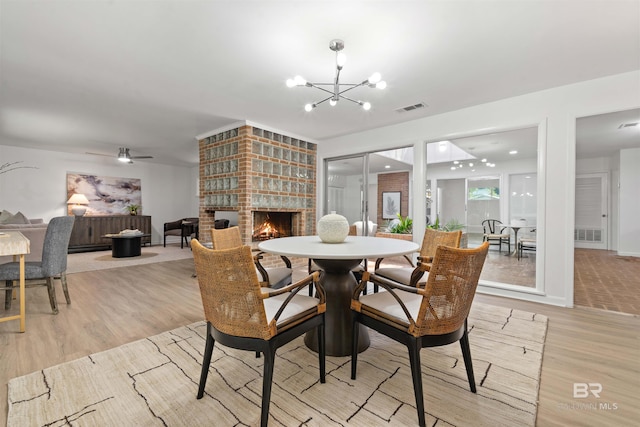 dining space with light wood-style floors, baseboards, a fireplace, and visible vents