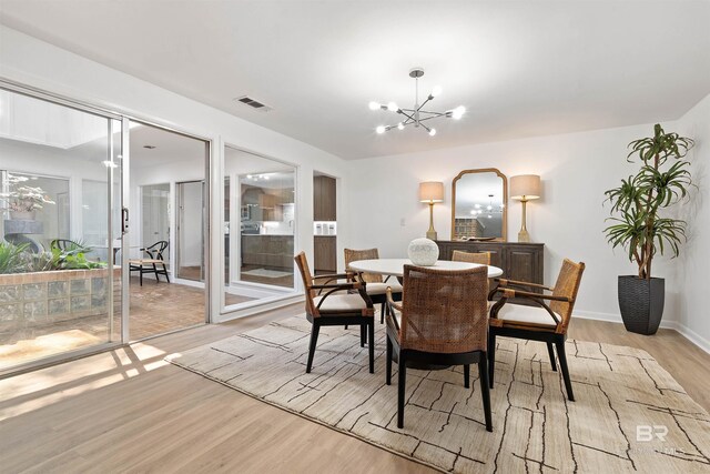 dining room with light hardwood / wood-style flooring, ceiling fan with notable chandelier, and a large fireplace