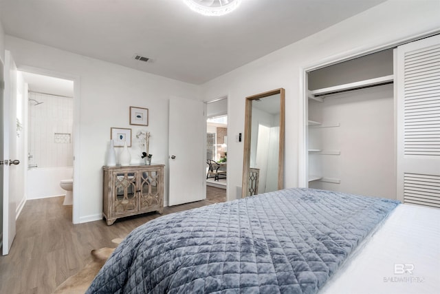 bedroom with a closet, visible vents, connected bathroom, and wood finished floors