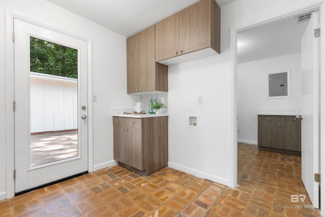 kitchen featuring visible vents, light countertops, brick floor, and electric panel