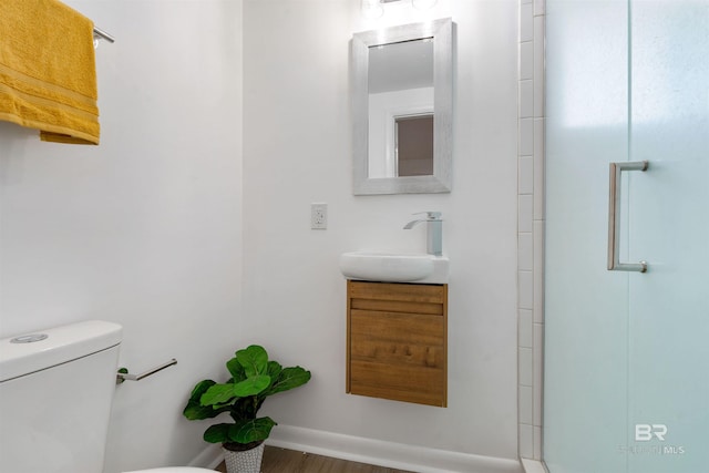 bathroom featuring a shower with door, vanity, and toilet