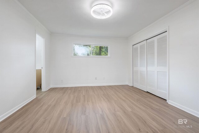 unfurnished bedroom with light wood-type flooring, crown molding, and baseboards