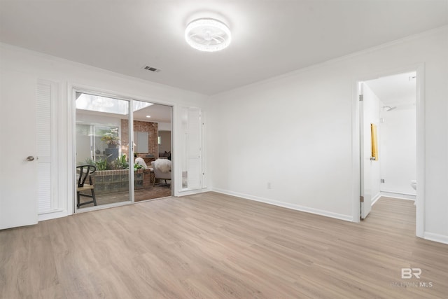 spare room featuring light wood-style floors, visible vents, ornamental molding, and baseboards