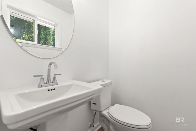 bathroom featuring toilet, baseboards, and a sink