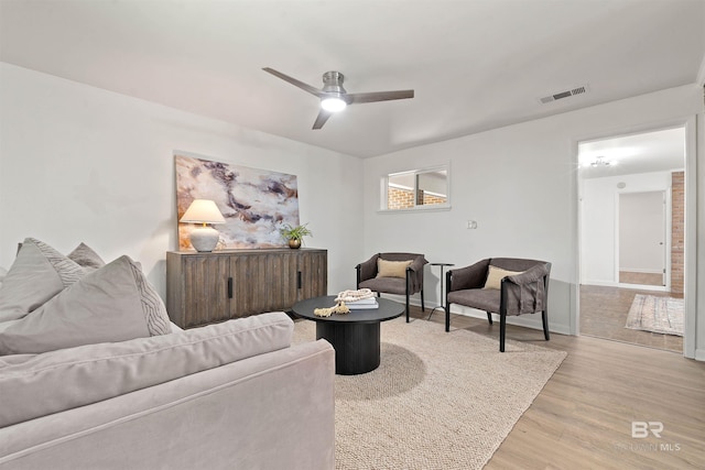 living room featuring ceiling fan, light wood-style flooring, visible vents, and baseboards