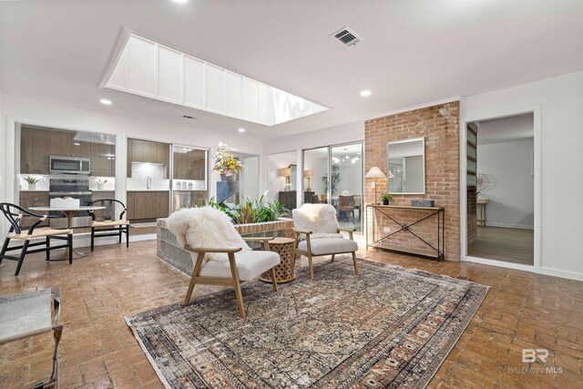 living room featuring ceiling fan with notable chandelier, a brick fireplace, and light hardwood / wood-style floors